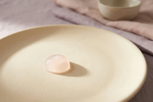 A drop of pale pink gel on matte cream ceramic